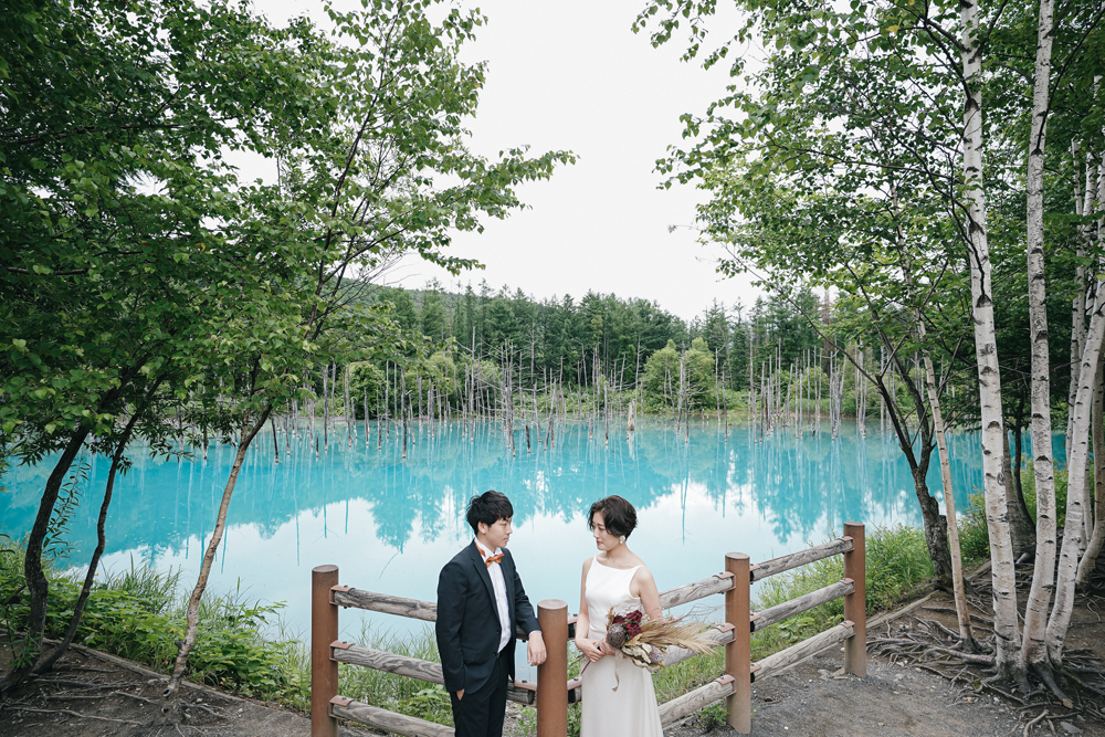 北海道・青い池の前撮り/フォトウェディングのロケーション撮影 | 青い池と緑の景色と一緒に。